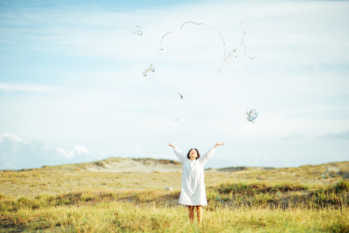 野原で両手を広げる女性の姿